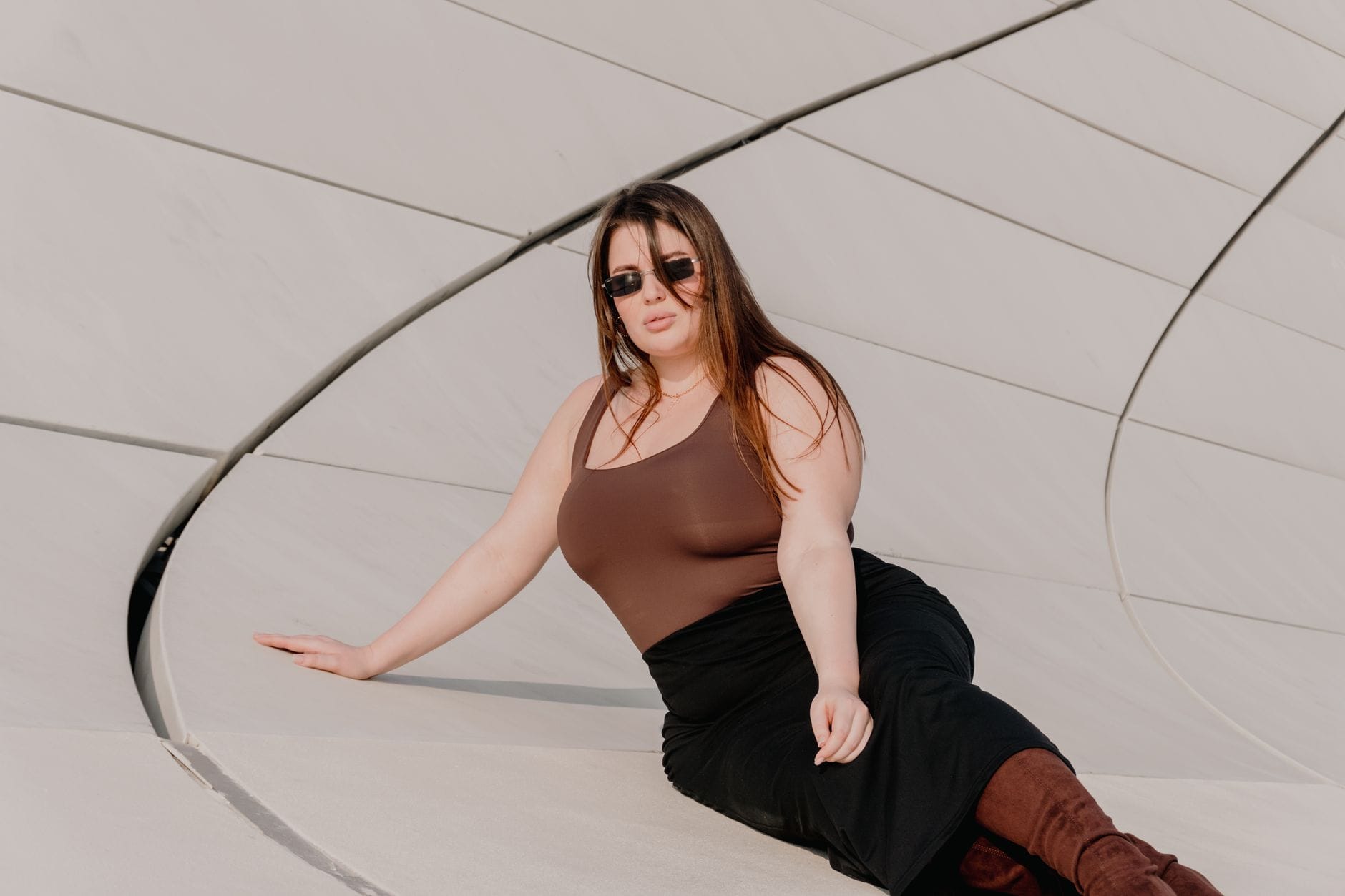 Kobieta plus size w modnej stylizacji pozuje na tle nowoczesnego budynku