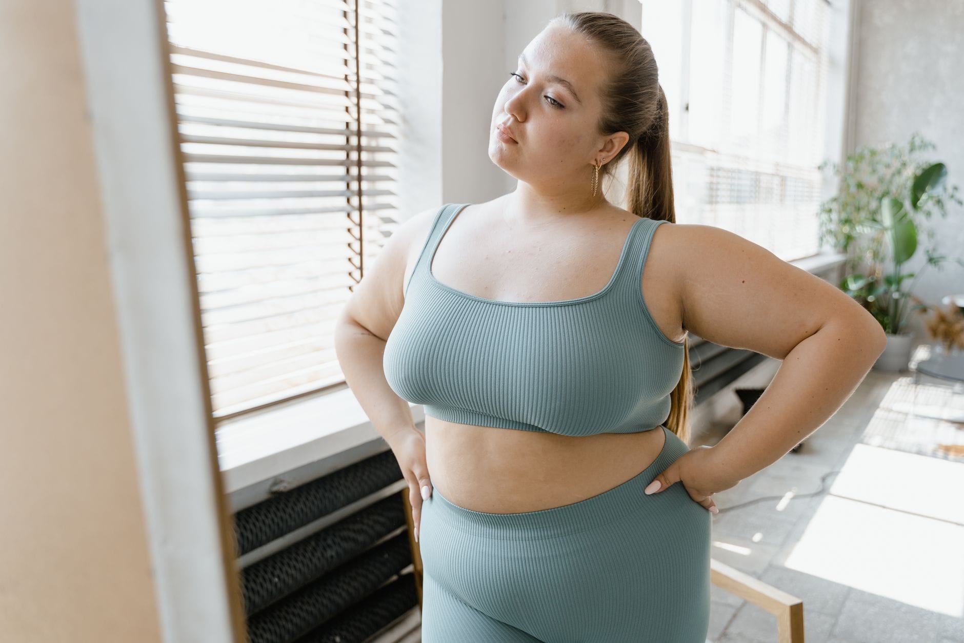 Pewna siebie kobieta plus size w sportowym stroju pozuje w pomieszczeniu