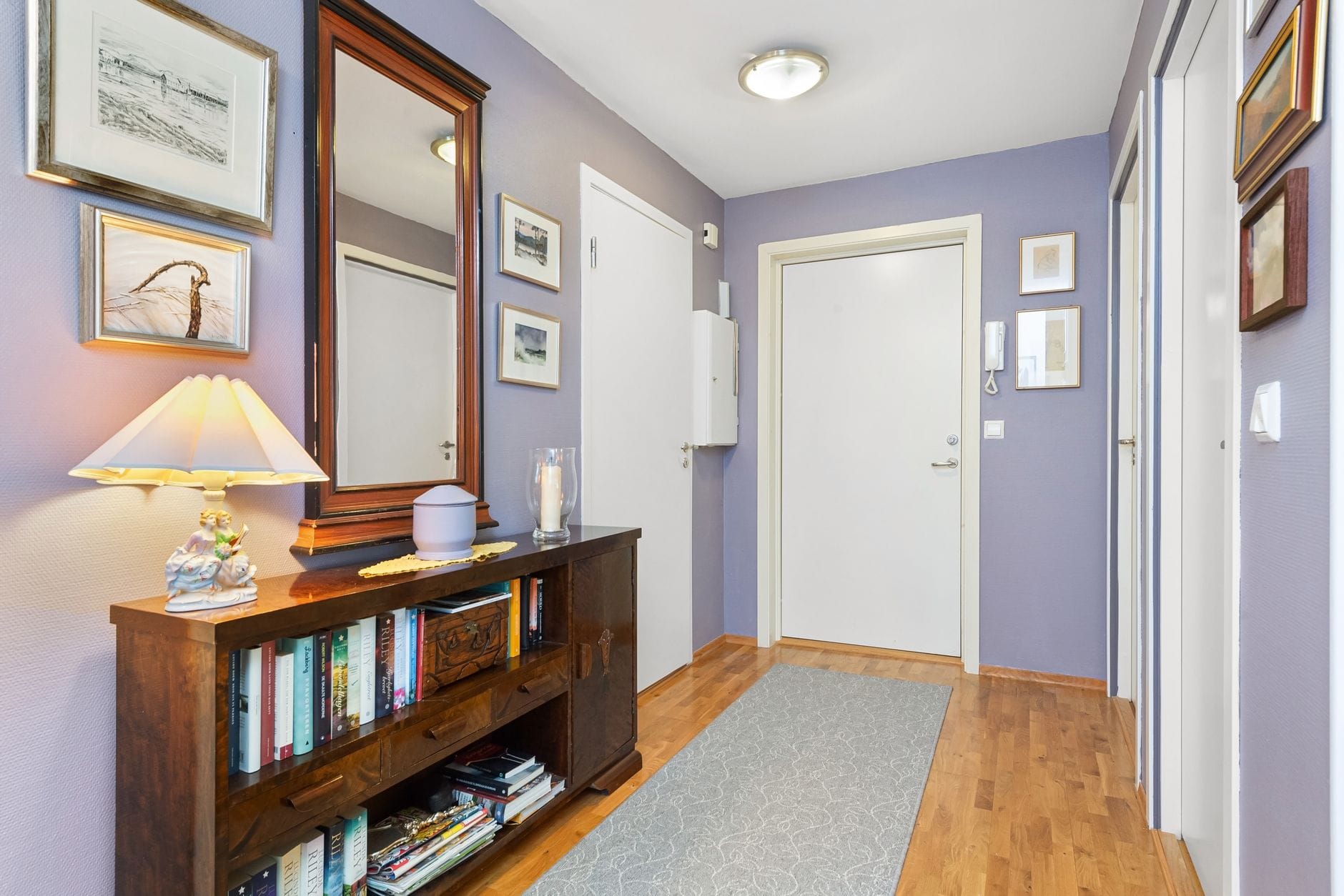 Maty i chodniki do korytarza jak wybrać antypoślizgowe i łatwe w czyszczeniu dywaniki do przedpokoju Przytulny korytarz z fioletowymi ścianami i drewnianym regałem